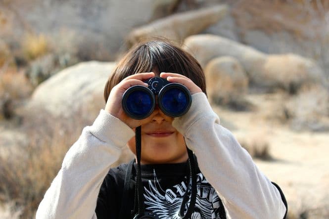 A young boy looking through binoculars.