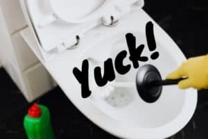 Image of someone trying to keep the toilet cleaner by using a scrub brush in the bowl. The word "Yuck!" is placed on top of the image.
