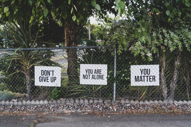Signs behind chain link fence saying not to give up.