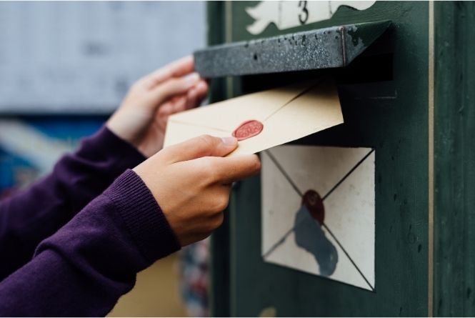 Make a child feel special on their birthday by mailing cards. This is an image of a hand putting a piece of mail into a mailbox.